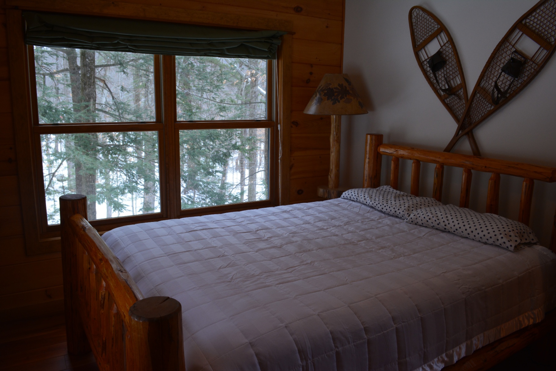 Bedroom with a rustic log-frame bed and snowshoes